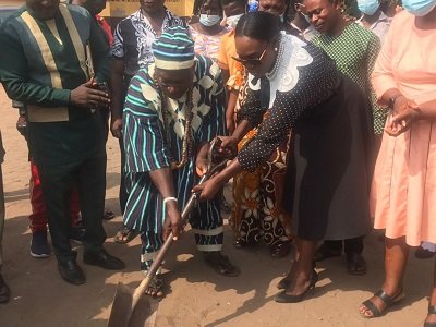 Ms Dakoa Newman being assisted by one of the elders to cut the sod for the construction of a kindergarten block