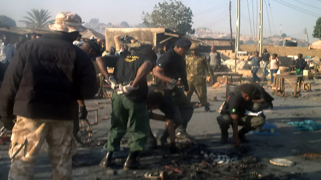 • A team of military and police bomb squad pick pieces of detonated explosives