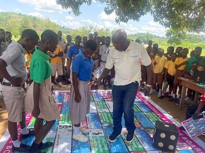 Mr Baabu demonstrating to some school children how the board game is played