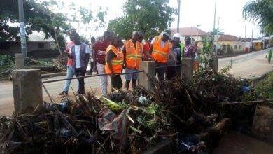 Mr Bossing and Ms Amewugah inspecting one of chocked gutters with refuse leading to flood at Ho- Bankoe