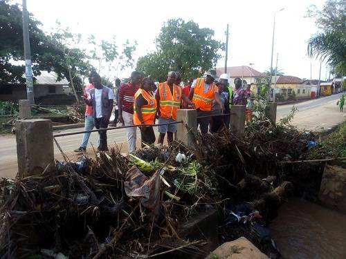 Mr Bossing and Ms Amewugah inspecting one of chocked gutters with refuse leading to flood at Ho- Bankoe