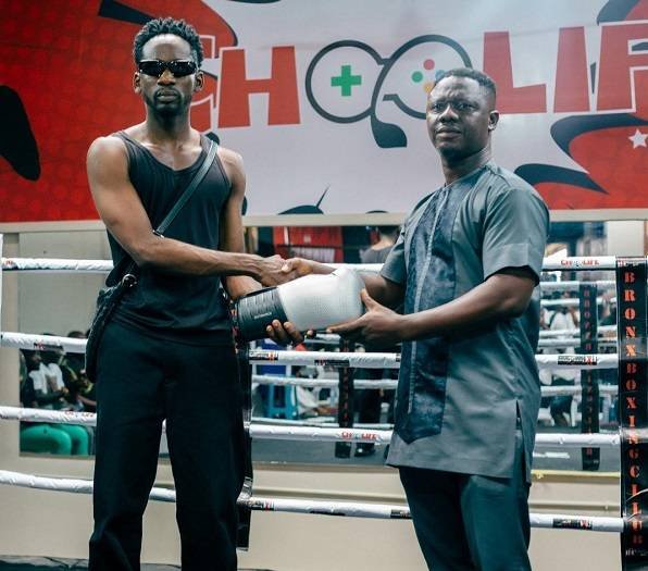 • Mr Eazi (left) presenting a glove to Mr Carl Lokko
