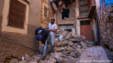 • Hussein Adnaie carries belongings out of his damaged house in Moulay Brahim