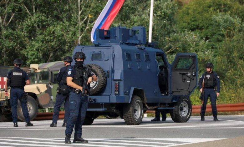 • Kosovo police at the scene with troops from the US and EU states in the background
