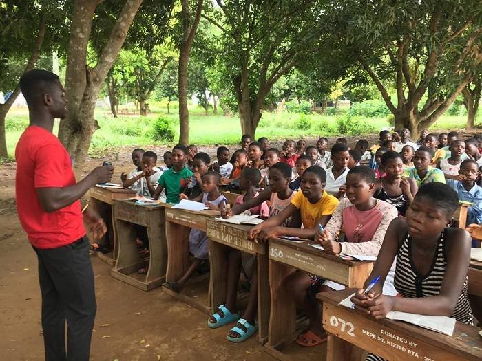 A teacher with the children under a tree