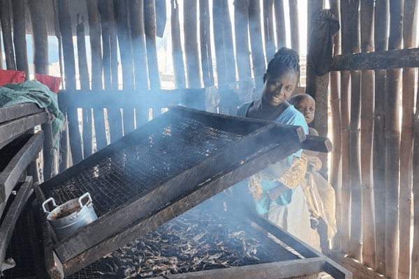 Ernestina with her baby on her back while smoking fish