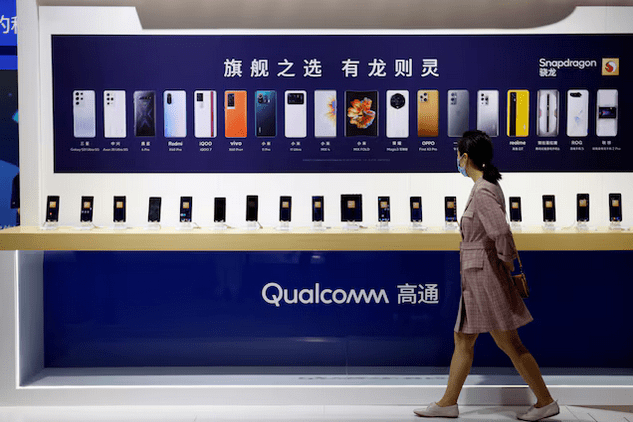 A woman walks past a counter displaying mobile phones at the Qualcomm booth during the 2021 China International Fair for Trade in Services (CIFTIS) in Beijing, China September 4, 2021. REUTERS/Florence Lo/File Photo Purchase Licensing Rights