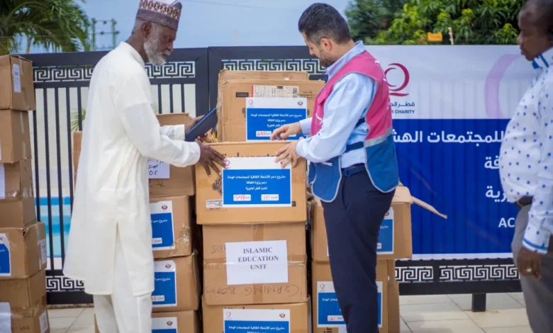 • A Qatar Charity official presenting books to a representative of recipient institutions
