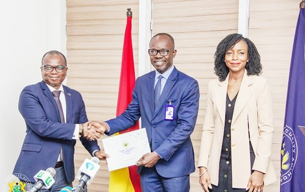 Seun Layade, Head of Project Management & Corporate Development and Acting Head of Technical and Professional Services at CWG Ghana (left) receiving the certificate or license from Dr. Albert Antwi-Boasiako, Director General, CSA.