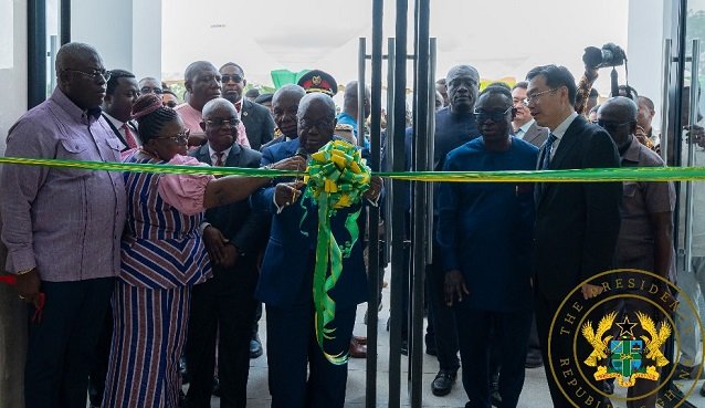 President Akufo-Addo (middle) being assisted to cut the tape to open the facility