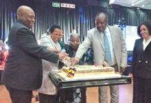 • Ms Mongella (middle) being assisted by Mr Charumbira (second right) and Clerk ( right) to cut the anniversary cake