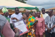 Mr.Ntim,in kente cloth, receiving the citation from Archbishop Anokye, left.