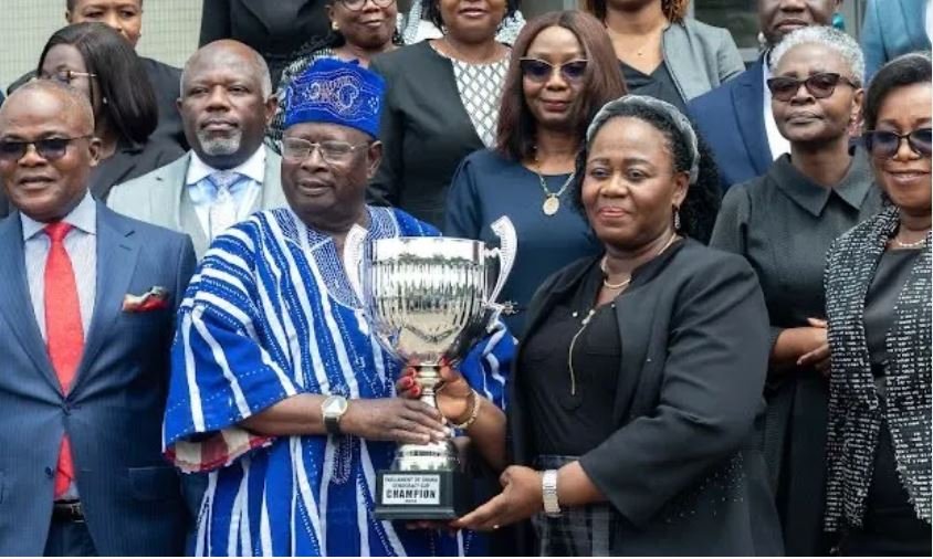 • Mr Cletus Avoka presenting the trophy to Justice Gertrude Torkonoo. Looking on are members of the judicial service and organisers of the match