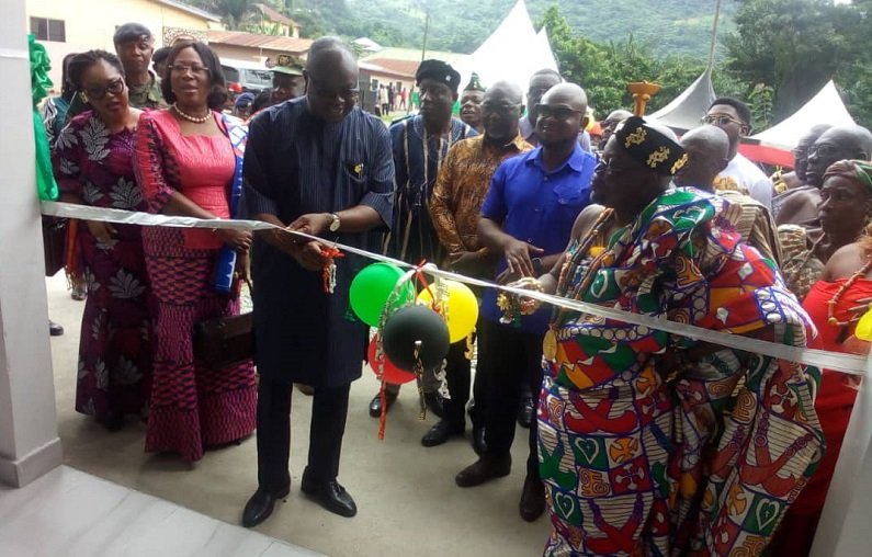 Mr Kwaku Ampratwum-Sarpong (second from left) being assisted by Chief of Leklebi -Kame, Togbe Atatsi V, (right) to cut the tape to open the facility