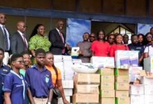 • Officials of GIA (left) presenting the items to some teachers of the school, while the students look on