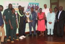 • A Samartex player presenting the trophy to Mr Allotey