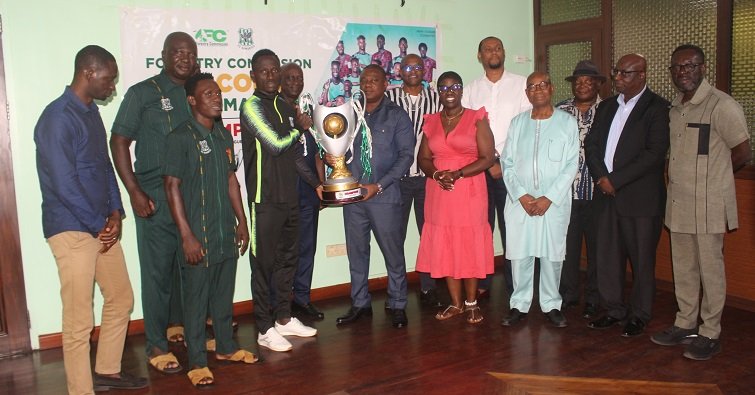 • A Samartex player presenting the trophy to Mr Allotey