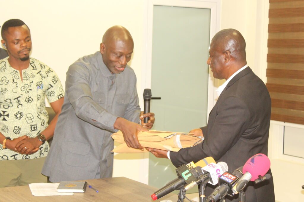 Mr Kofi Koranten (middle) Independence presidential candidate presenting his document to Mr Samuel Tetteh, Deputy Commissioner in charge of Operations, EC