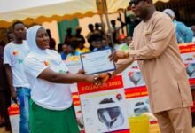 Alhaji Farouk Aliu Mahama presenting an item and certificate to one of the beneficiaries