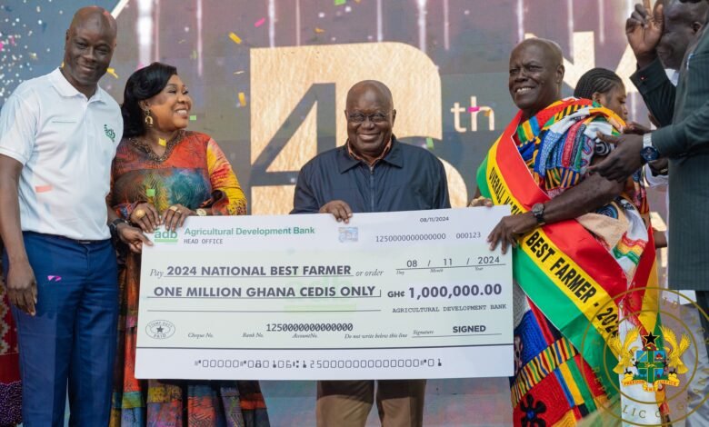 President Akufo-Addo ( middle) being assisted by other dignitaries to present the 2024 overall National Best Farmer dummy cheque to Nana Owusu Achiaw (right). Photo Victor A. Buxton