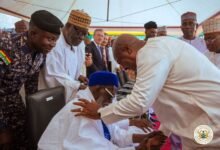 President Mahama, bowing, in a handshake with the National Chief Imam seated