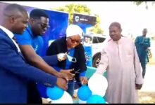 Mr Mubarak Abdulai being assisted with some staff of the bank and a member of Kpalsi community to cut the tape to inaugurate the borehole