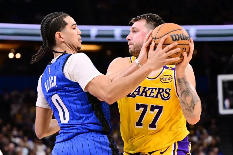 • Luka Doncic, right, of the Los Angeles Lakers looks to pass the ball against Anthony Black #0 of the Orlando Magic