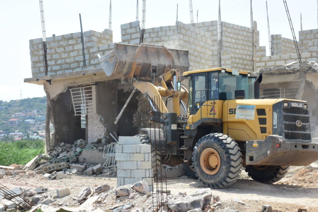 A Bulldozer pulling down an uncompleted storey building