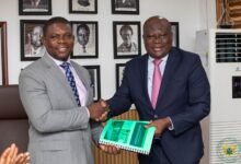 Mr Richard Gyan Mensah (left) receiving the report from Mr Kirk Koffi at the programme