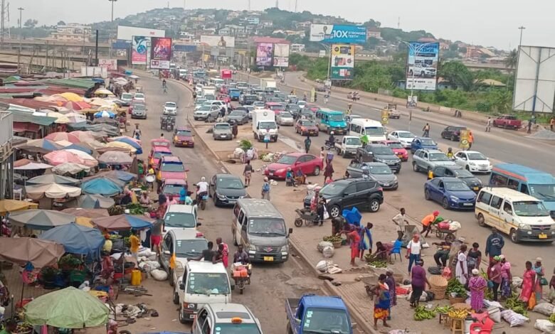 Traders busily selling on the pavement of the Mallam market road.