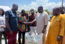 • Mr Dumelo (second from right), presenting a bag of fertiliser to the farmers