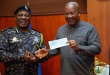 President Mahama (right) receiving the cheque from IGP Christian Tetteh Yohuno