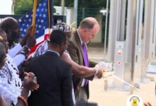 • Mr Rolf Olson, Charge d'Affaire at US Embassy, being assisted by Dr Hammond to commission the plant