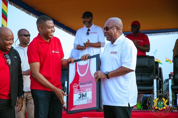 • MD of Absa Bank Ghana, Mr Botchway (left) presenting a customised framed jersey to President Mahama