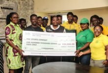 • Madam Commodore-Toppar (arrowed) presenting a dummy cheque to Madam Obuobisa-Atakora (standing left)