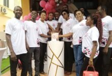 • Mrs Baitie (third from right) being assisted by other staff to cut the anniversary cake