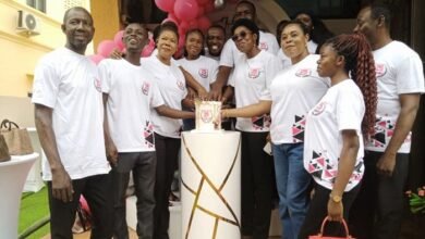 • Mrs Baitie (third from right) being assisted by other staff to cut the anniversary cake