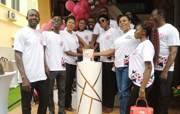 • Mrs Baitie (third from right) being assisted by other staff to cut the anniversary cake