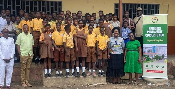 • Ataa Lartey and Mr Jerry Ahmed (extreme left) with some of the pupils and teachers of the academy and Parliamentary staff