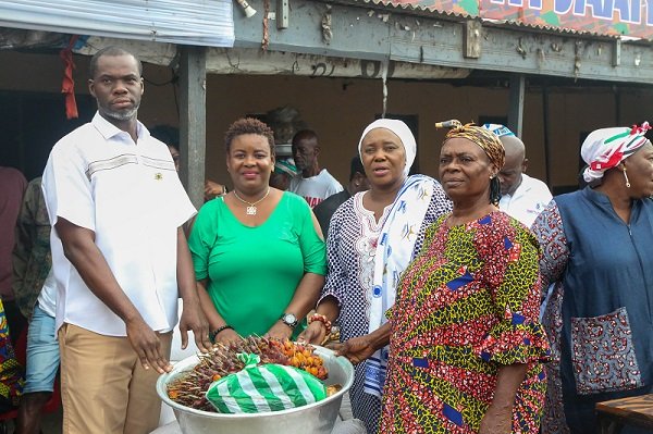 • Ms Sowah (second from right) and Mr Anyetei (left) assisting a beneficiary with items (inset)