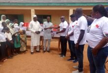 • Leonard Edem Cosmos, presenting the items to Alhaji Haruna Mohammed, Headmaster of Moree Junction Islamic Basic School.