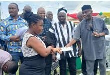 • Mr John Kwadwo Gyapong handing over cash envelope to a beneficiary