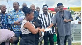 • Mr John Kwadwo Gyapong handing over cash envelope to a beneficiary