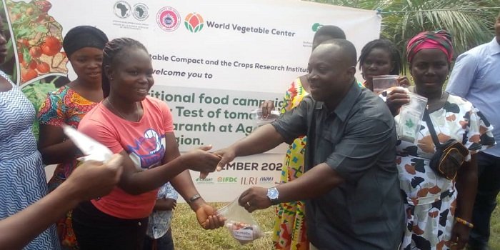 • Dr Michael Kwabena Osei (right) presenting samples of the new tomato seeds to farmers