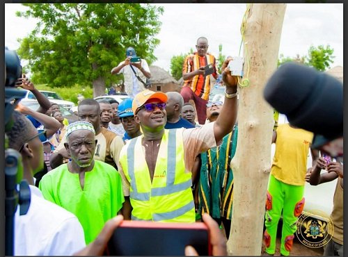 • Mr Jinapor (inset) switching on the lights. With him are some members of the communities