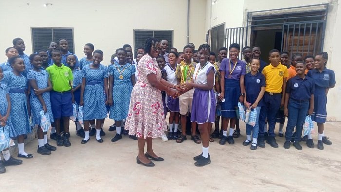 • Madam Mary Dagba presenting a trophy to Jamverson School