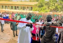 Dr Mohammed Amin Adam being assisted by Mr Abukari Yakubu to cut the tape to officially open the block