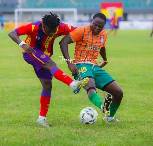 A Vision FC player (right) moves in to block a shot from a Hearts of Oak attacker