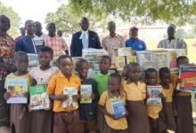 Lamtiig Apanga (in suit),with community leaders, learners at Sakoti after handing over books and other learning materials to schools