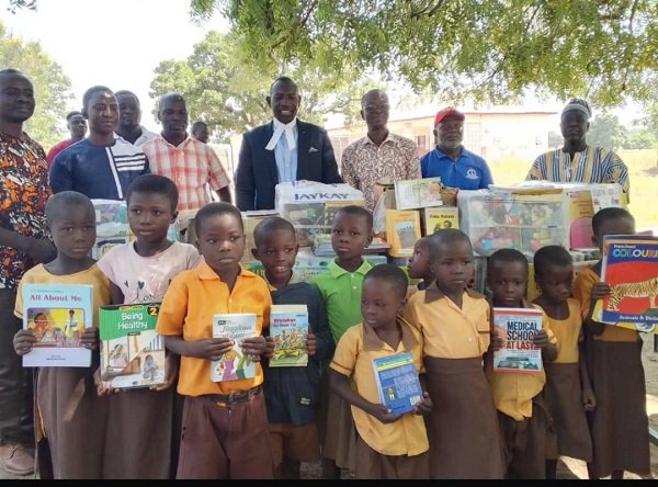 Lamtiig Apanga (in suit),with community leaders, learners at Sakoti after handing over books and other learning materials to schools